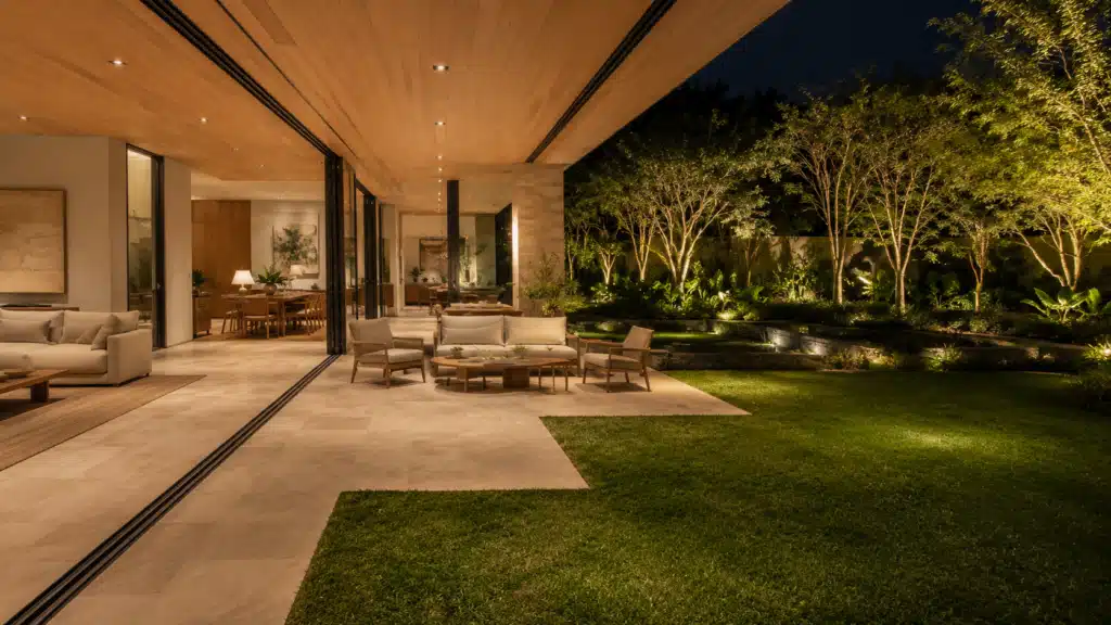 Sala integrada à varanda com esquadria de correr e jardim ao fundo — projeto It Arquitetura