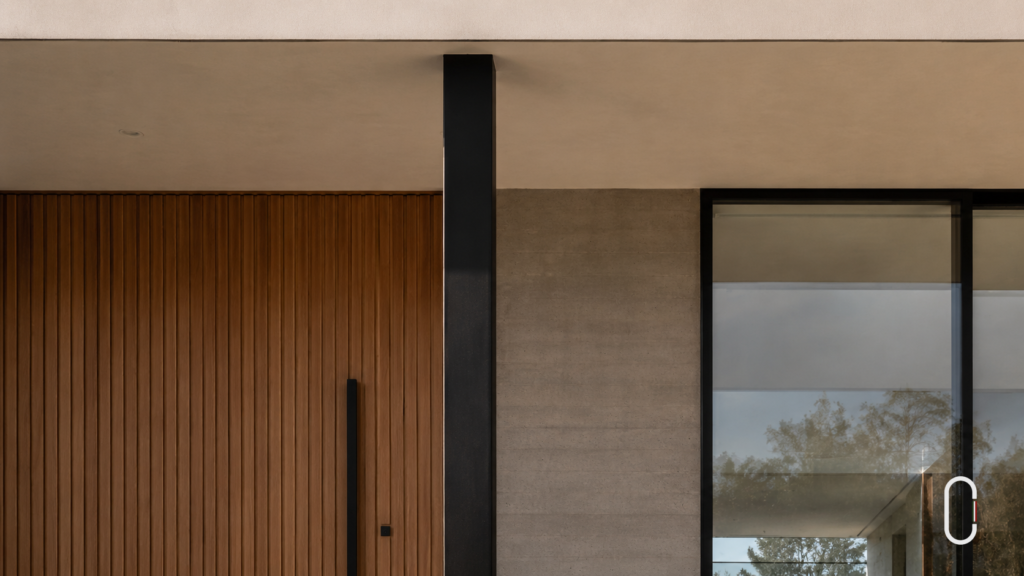 Detalhe de fachada minimalista com concreto aparente, madeira ripada, vidro e acabamento preciso.