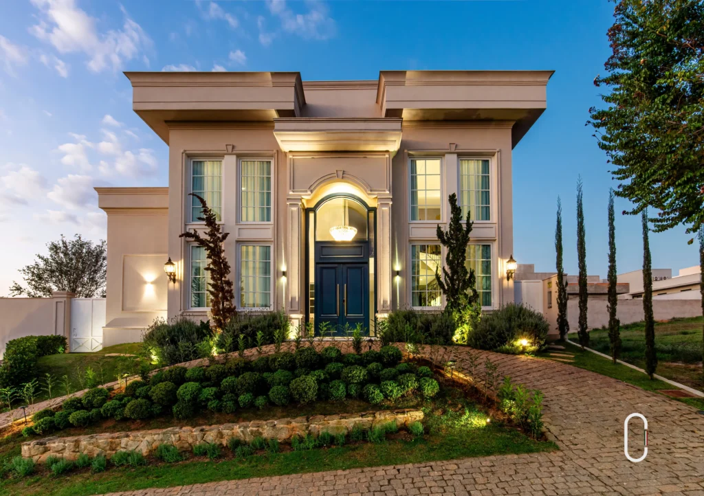 Residência estilo Italico com fachada clara, molduras retas, porta imponente e paisagismo